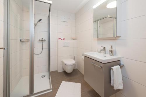 a white bathroom with a shower and a sink at Millegga Grächen in Grächen