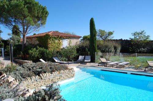 a swimming pool with chairs and a house at Cyprès du Paradis à Gordes in Gordes