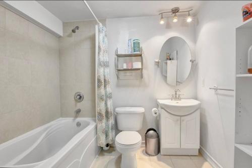 a white bathroom with a tub and a toilet and a sink at A very peaceful home in Oshawa