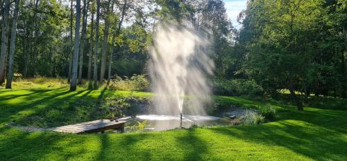 a fountain in a park with a bench next to a pond at Chaloupky U Matušků in Varnsdorf