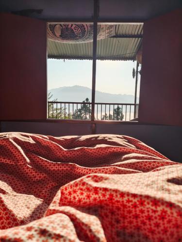 a bed with a patterned blanket on it with a window at Nuwakot Hills Farmstay in Trisūli Bāzār