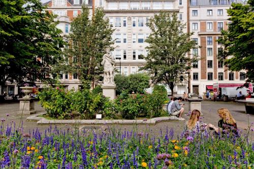 two girls sitting in a garden with flowers in front of a building at 37GS Residences in London