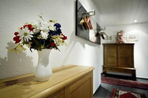 a white vase filled with flowers sitting on a table at White Summit Appartement in Vandans
