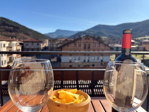 a table with two wine glasses and a bowl of chips at Itxinako Balkoia in Murueta-Orozko