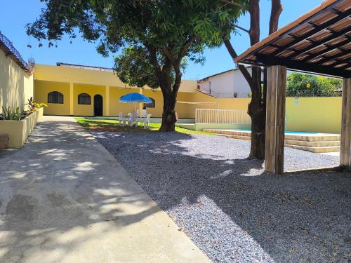 a yellow building with a table and a blue umbrella at Casa Alegria até 9 pessoas, Piscina, Churrasqueira, Empresas e Grupos in Montes Claros
