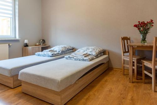 two beds in a room with a table and a desk at Noclegi GCK Biała in Biała