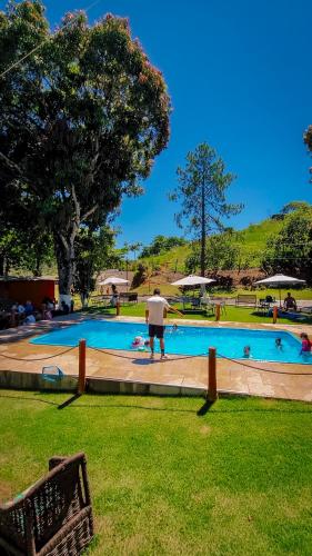 a man standing in front of a swimming pool at Seleto Hotel Fazenda in Arrozal