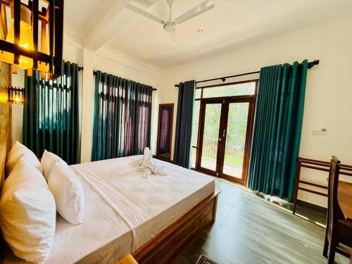a bedroom with a large bed with green curtains at Cormorant Bath in Netolpitiya