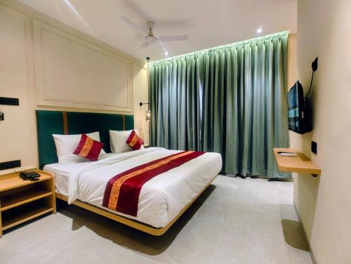 a bedroom with a large bed and a television at Kubo by Convivial Hotels in Raipur