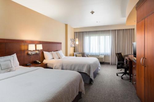 a hotel room with two beds and a desk at Courtyard by Marriott Ontario Rancho Cucamonga in Rancho Cucamonga