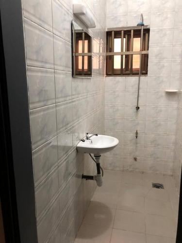a white bathroom with a sink and a window at Mariagletta Cozy Villa in Abomey-Calavi