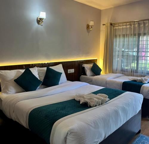 a hotel room with two beds with towels on them at Umai Garden Resort in Jogīkuti