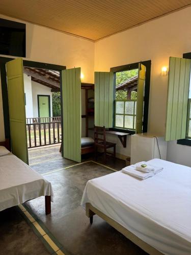 a bedroom with two beds and a balcony at Pousada do Ipe in Goiás