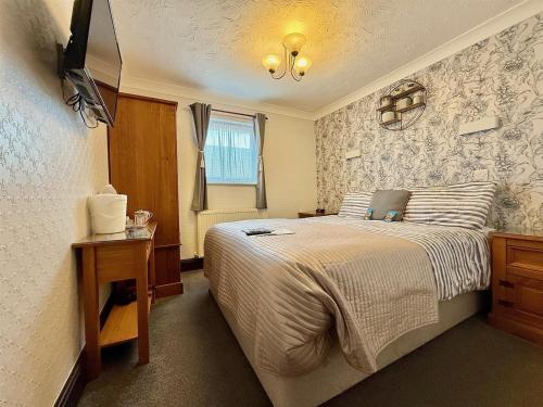 a bedroom with a bed and a table and a window at Maluth Lodge in Great Yarmouth