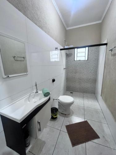 a white bathroom with a toilet and a sink at Casa luz e conforto Passos Capitólio in Passos