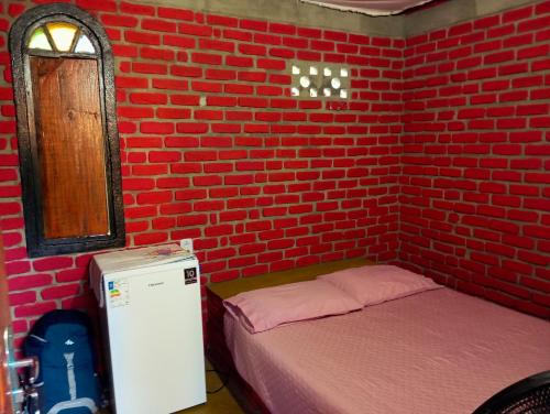 a room with two beds and a brick wall at Bangalo O Galo in Itacaré