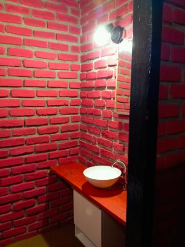 a bathroom with a red brick wall and a sink at Bangalo O Galo in Itacaré
