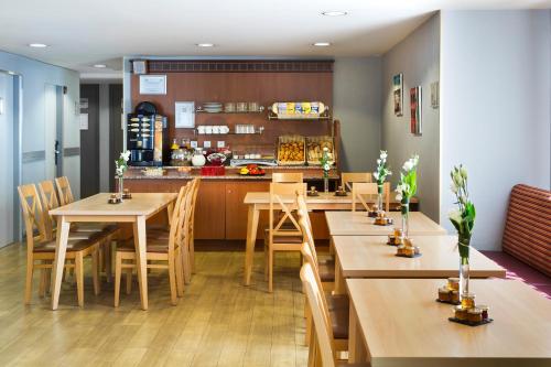 un restaurant avec des tables et des chaises en bois et une cuisine dans l'établissement Citadines Prado Chanot Marseille, à Marseille