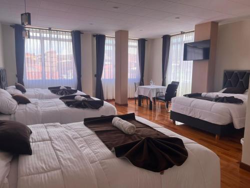 una camera d'albergo con tre letti e una sala da pranzo di Hostal Alvasar a Copacabana