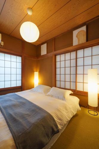 a bedroom with a large bed in a room with windows at Tachikawa City 3LDK Private House in Tachikawa