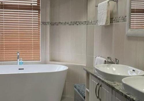 a white bathroom with a tub and a sink at Moon Landscape Self Catering in Swakopmund