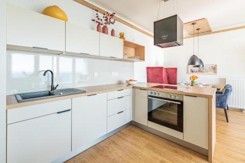 a kitchen with white cabinets and a sink and an oven at Ferienwohnung Seeloge im Bollwark Olpenitz in Olpenitz