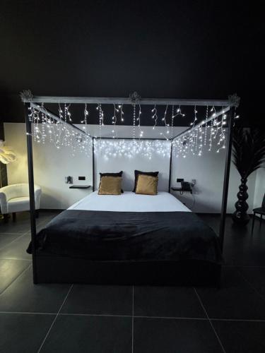 a bedroom with a canopy bed with christmas lights at Le Bovary Hotel Suite Diamond in Héron