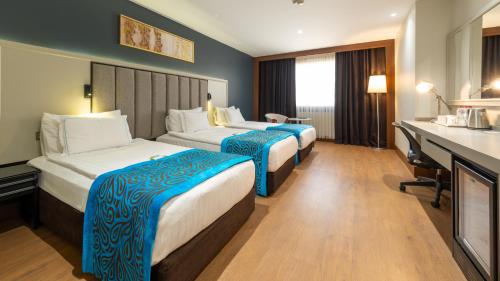 a hotel room with two beds and a desk at Teymur Continental Hotel in Gaziantep