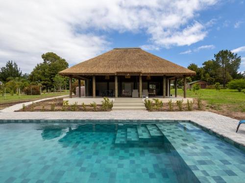 a pavilion with a swimming pool in front of a building at Five Elements Resort - Nguni Cabin in Harkerville