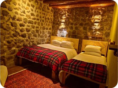 two beds in a room with a stone wall at MiNKA HOUSE in Hisarcık