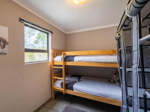 a bedroom with bunk beds and a window at Five Elements Resort - Nguni Cabin in Harkerville