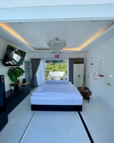 una camera da letto bianca con un grande letto e un lampadario di บ้านสวนจมูกโต a Ban Pha Mi
