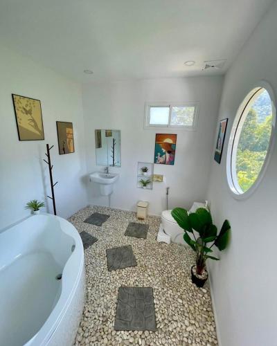 un bagno con una vasca e una pianta dentro di บ้านสวนจมูกโต a Ban Pha Mi