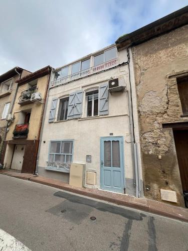 an old building with a blue door on a street at Écrin Secret - Suite troglodyte avec spa in Pia