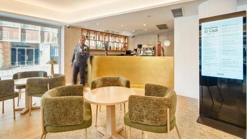 a man standing in a room with a table and chairs at Sercotel HMO Martina in Granada