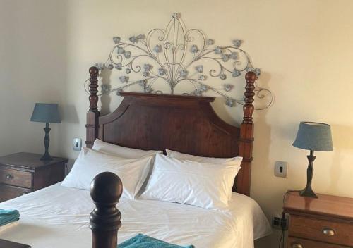 a bed with a large wooden headboard and white sheets at Moon Landscape Self Catering in Swakopmund