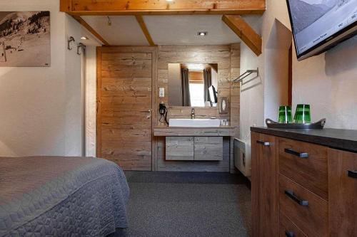 a bedroom with a bed and a bathroom with a sink at Berghotel TheLounge in Berwang