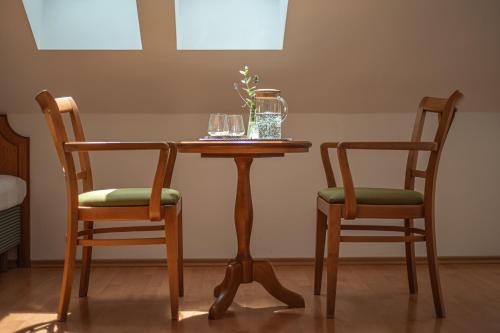 a wooden table and two chairs with glasses on it at Penzion Tematin in Piešťany