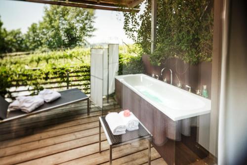 a bathroom with a bath tub and a chair at Weingartenhotel Harkamp Südsteiermark in Sankt Nikolai im Sausal