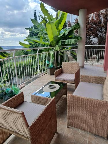 a patio with wicker chairs and tables on a balcony at Panoráma apartman in Pécs