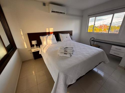 a bedroom with a white bed with towels on it at Apartamentos amoblados de 1, 2 y 3 dormitorios in Nueva Ola