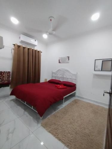 a bedroom with a red bed with a red blanket at Akiera Homestay #MELAYU ONLY in Pelabuhan Kelang