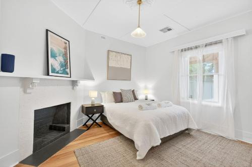 a white bedroom with a bed and a fireplace at The Wharf House Goolwa in Goolwa