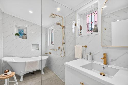 a white bathroom with a sink and a tub at The Wharf House Goolwa in Goolwa