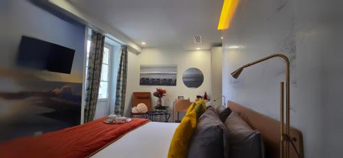 a bedroom with a bed and a tv on the wall at Le Petit Trianon et le Charme des Suites in Nice