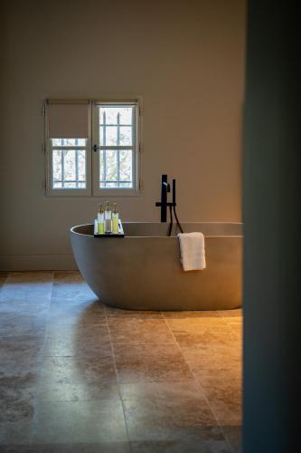 a bath tub in a bathroom with a window at Hotel La Bastide d'Eygalières in Eygalières