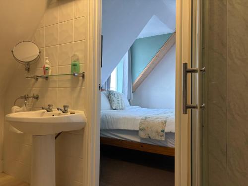 ein Badezimmer mit Waschbecken und ein Bett in einem Zimmer in der Unterkunft Captain Howey Hotel in New Romney