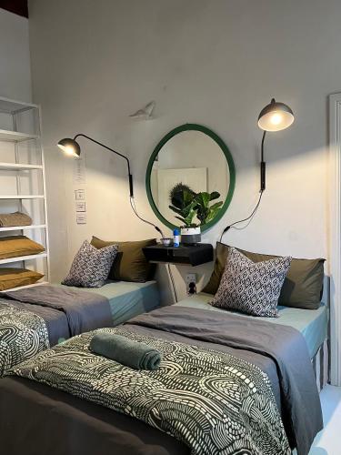 two beds in a room with a mirror on the wall at Calitzdorp Self-Catering Guesthouse - Oudehuis in Calitzdorp