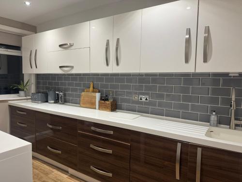 a kitchen with white cabinets and a sink at The Clock Tower Apartment - Spacious, Modern, 2 Bedroom Apartment , Southsea with Free parking - sleeps 4 in Portsmouth