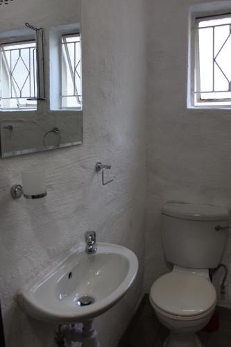 a white bathroom with a toilet and a sink at Sunlit Retreat Private Flatlet with Solar Power Pool Fast WiFi & Secure Parking in Roodepoort